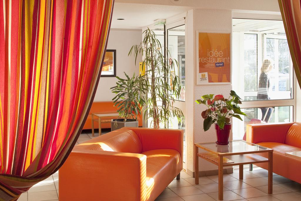 Salon moderne avec rideaux colorés et canapés orange.
