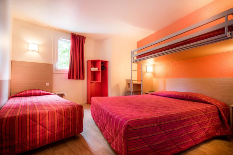 Chambre d'hôtel avec lits et décoration rouge.