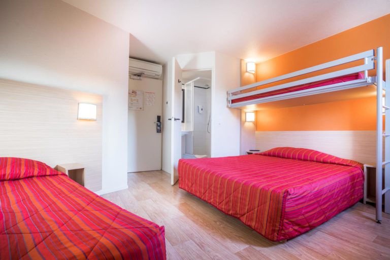 Chambre d'hôtel avec lit double et lit superposé.