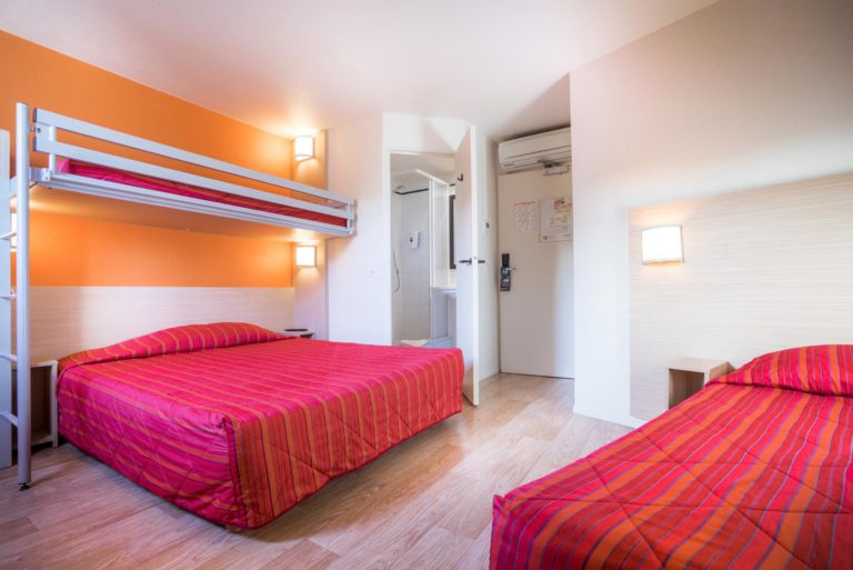 Chambre d'hôtel avec lits superposés, lit double, salle de bain.