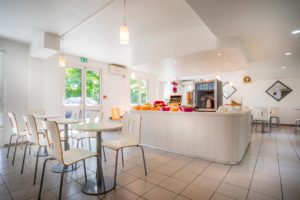 Cafétéria moderne avec tables et chaises blanches.