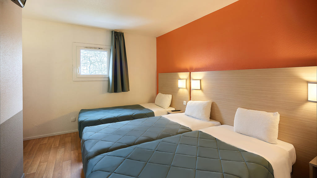 Chambre moderne avec trois lits simples.