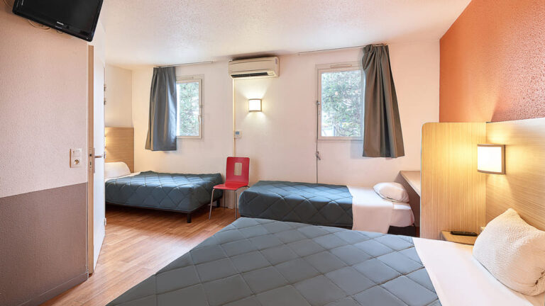 Chambre d'hôtel moderne avec trois lits.