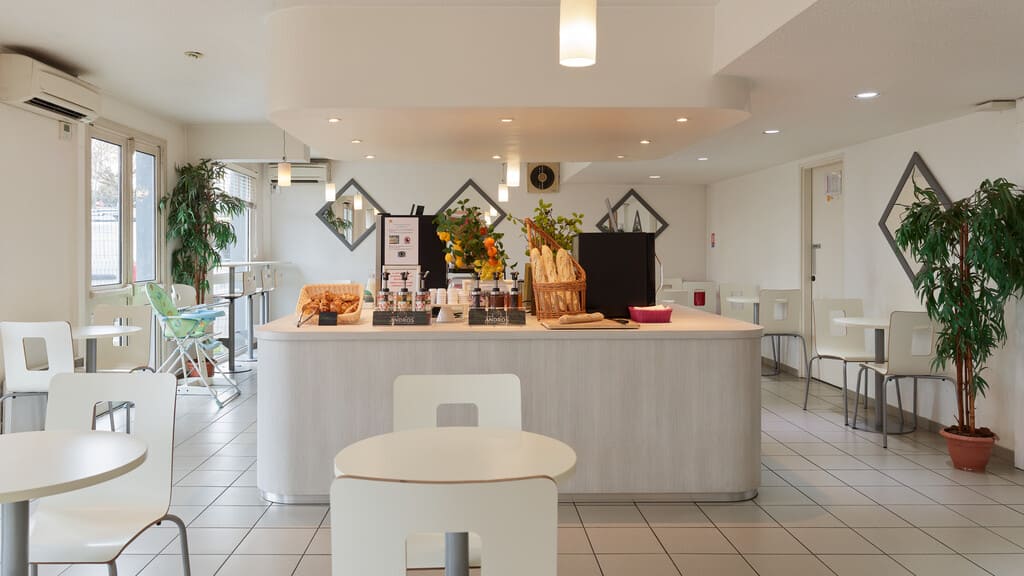 Café moderne avec comptoir et tables blanches.