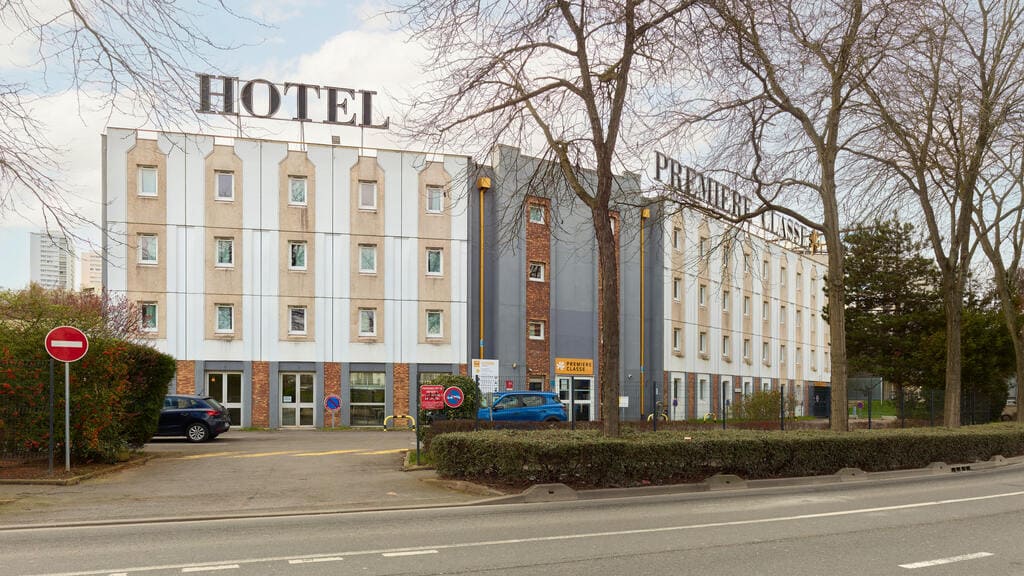 Façade d'un hôtel avec parking devant.
