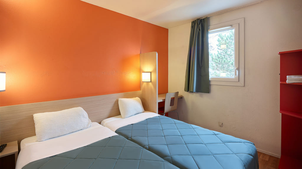 Chambre d'hôtel avec deux lits simples.