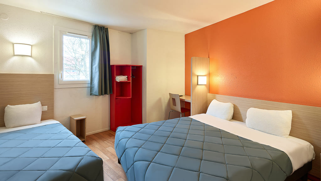 Chambre d'hôtel avec deux lits, murs orange.
